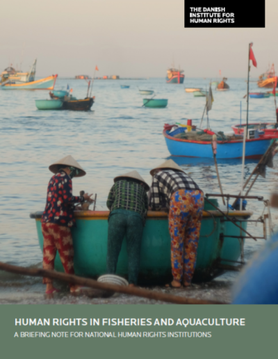 A photo showing three people standing by a small fishing vessel in the foreground, a body of water in the background, with small fishing vessels floating on the water's surface